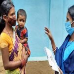 An ASHA worker conducting a home health check-up for a newborn and mother.